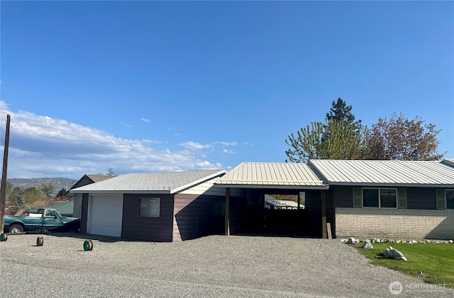view of front of home featuring brick siding, driveway, a carport, and a garage