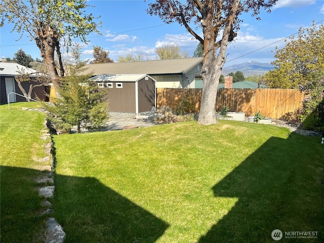 view of yard featuring fence, a storage unit, and an outbuilding