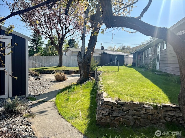 view of yard featuring a storage shed, an outbuilding, and fence