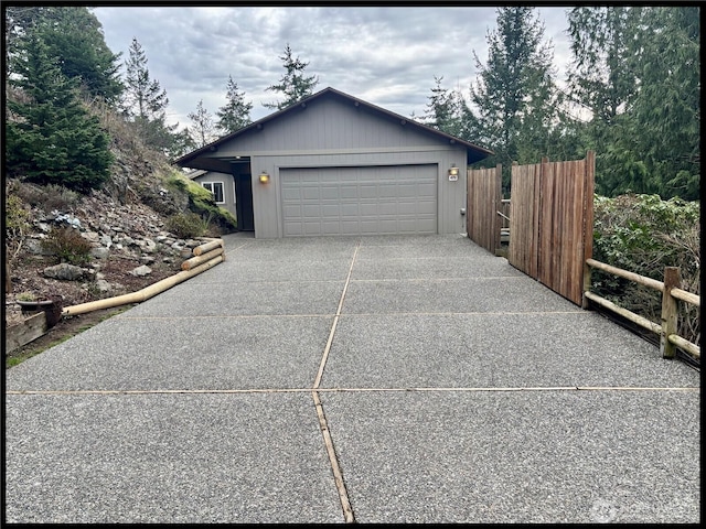 garage featuring concrete driveway and fence