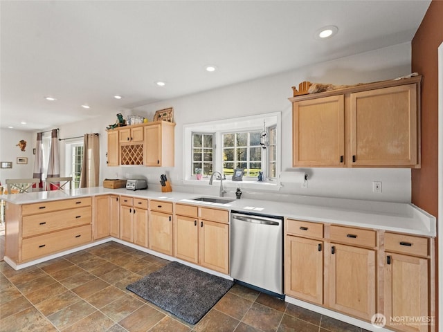 kitchen featuring light brown cabinets, a peninsula, a sink, light countertops, and dishwasher