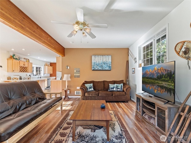 living room featuring ceiling fan, visible vents, baseboards, light wood-style floors, and beamed ceiling