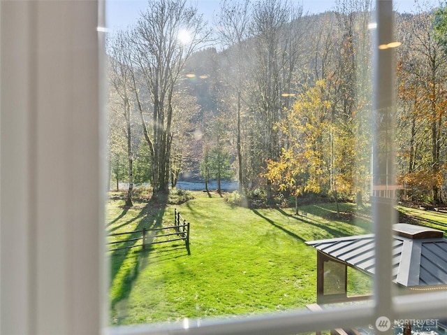 view of home's community featuring a lawn and a wooded view