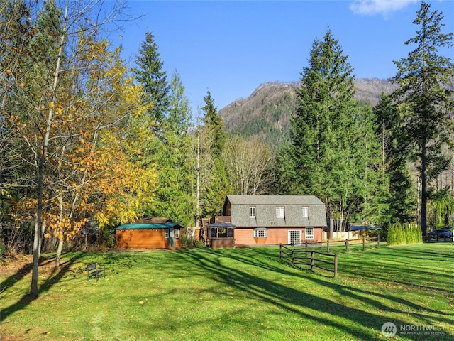 view of yard featuring fence, a view of trees, and a mountain view