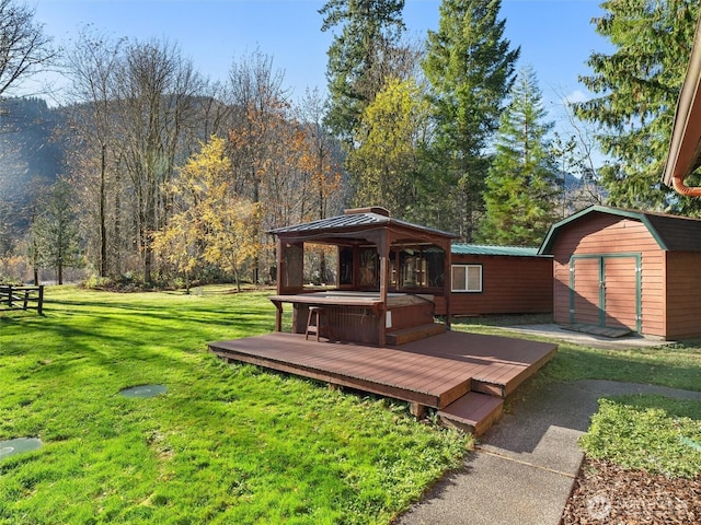 wooden deck featuring a storage shed, a lawn, an outbuilding, a gazebo, and a wooded view