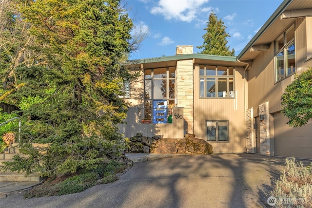 exterior space featuring stone siding and a chimney