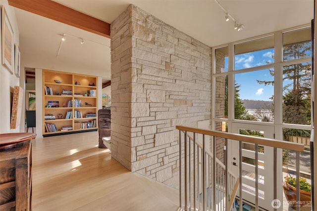 corridor with track lighting, expansive windows, an upstairs landing, and wood finished floors