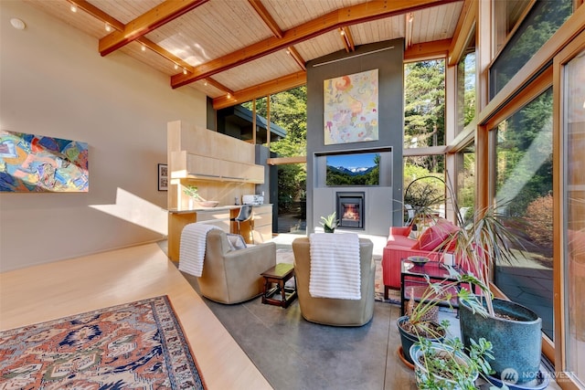 interior space with a towering ceiling, wood ceiling, beam ceiling, floor to ceiling windows, and a glass covered fireplace