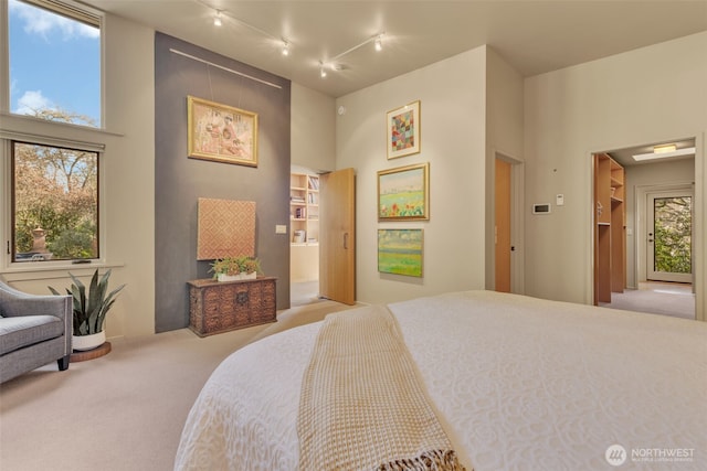 bedroom with a towering ceiling, multiple windows, and carpet flooring