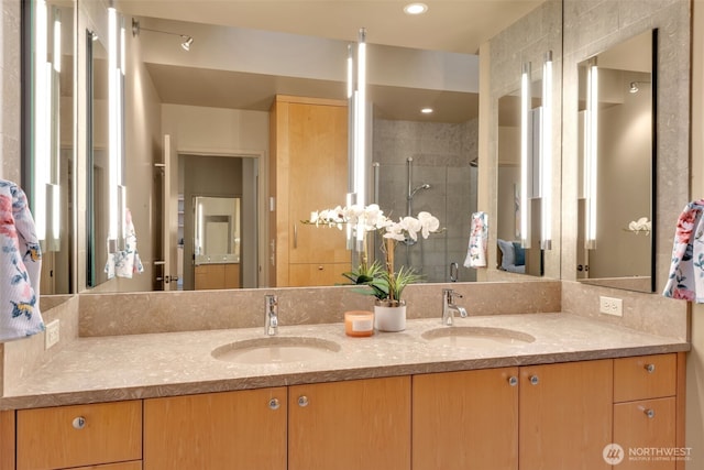 bathroom featuring double vanity, a stall shower, a sink, and recessed lighting