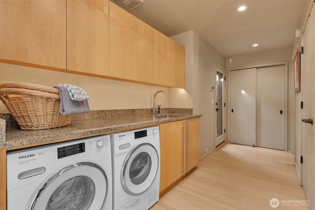 laundry room featuring cabinet space, light wood finished floors, washer and clothes dryer, a sink, and recessed lighting