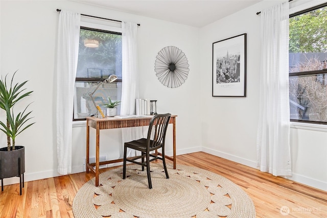 home office with wood finished floors, a healthy amount of sunlight, and baseboards