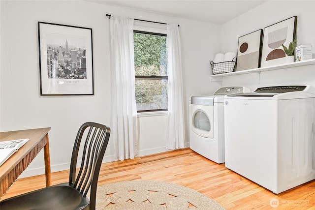 clothes washing area featuring washing machine and clothes dryer, laundry area, baseboards, and light wood-style floors