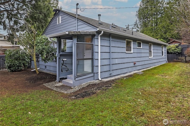 view of side of property featuring a lawn and fence