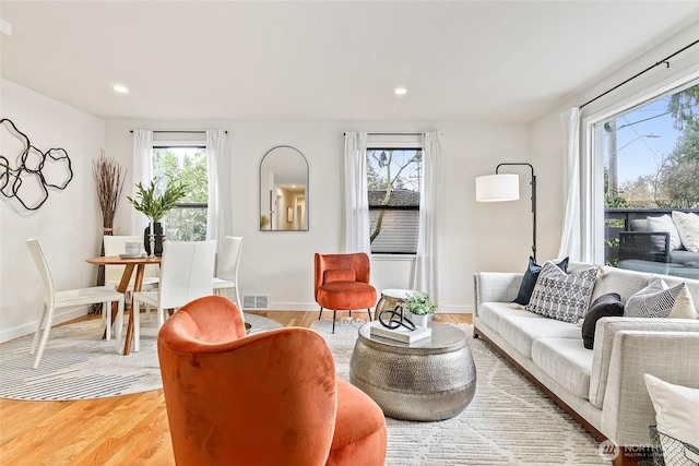 living area featuring a wealth of natural light, visible vents, light wood-style flooring, and recessed lighting