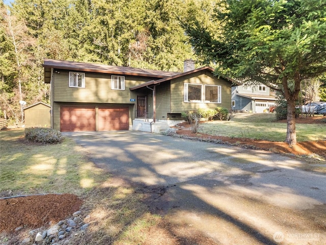 view of front facade featuring aphalt driveway, a front lawn, a chimney, and an attached garage