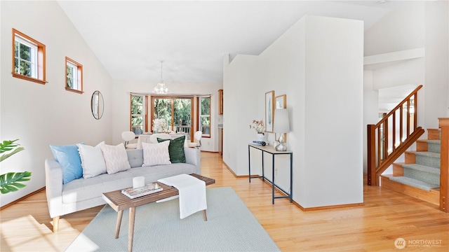 living area featuring light wood finished floors, baseboards, stairway, vaulted ceiling, and a notable chandelier