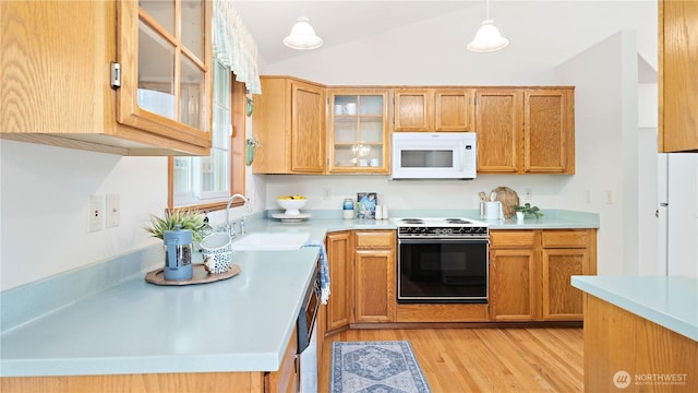 kitchen with light wood finished floors, white appliances, light countertops, and a sink