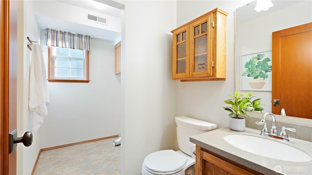 half bath featuring vanity, toilet, and visible vents