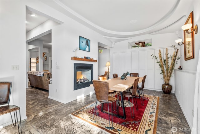 dining area featuring a glass covered fireplace and baseboards