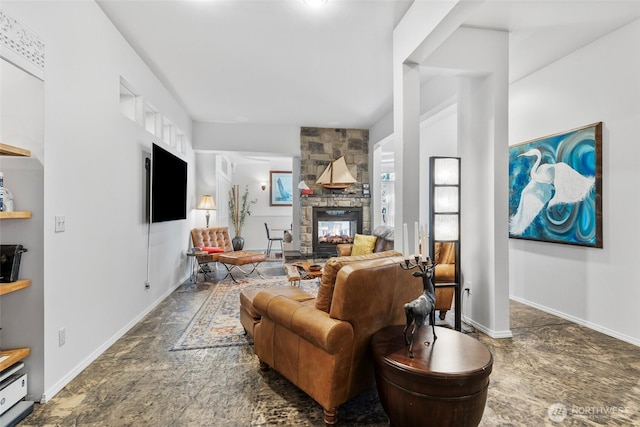 living area featuring stone finish floor, a stone fireplace, and baseboards