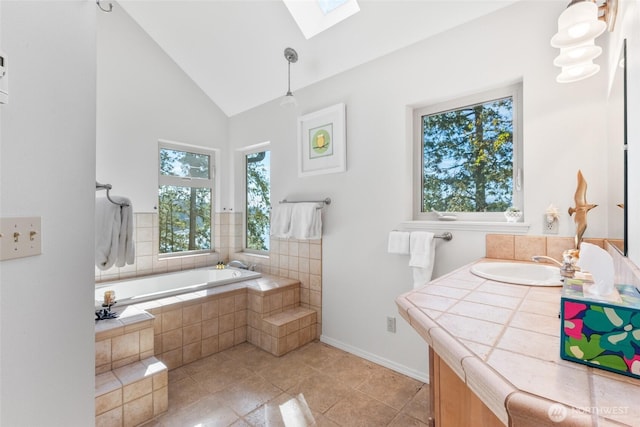 bathroom featuring a garden tub, vaulted ceiling with skylight, a wealth of natural light, and vanity