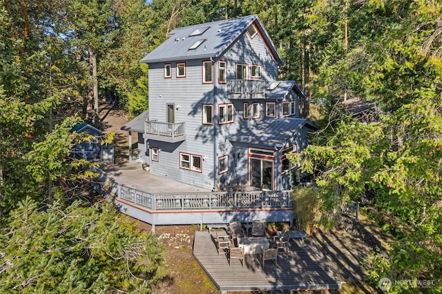 rear view of property featuring a wooden deck and a balcony