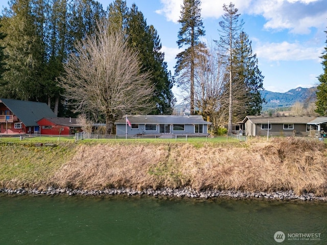 back of property featuring a water and mountain view and fence