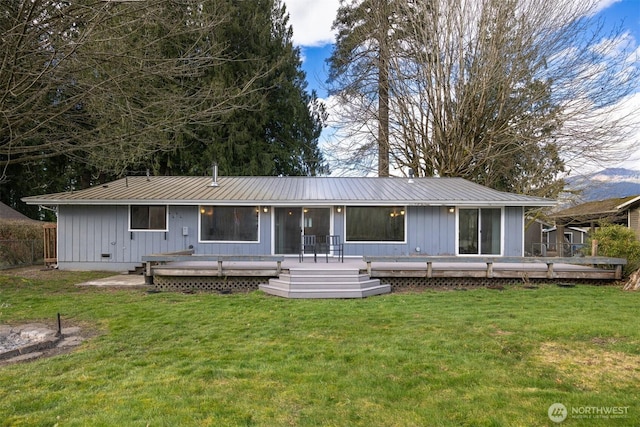 rear view of property featuring a deck, a lawn, and metal roof