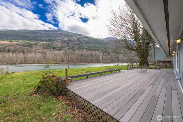 wooden deck featuring a water and mountain view and a lawn