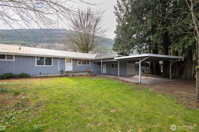 rear view of house with a lawn and metal roof