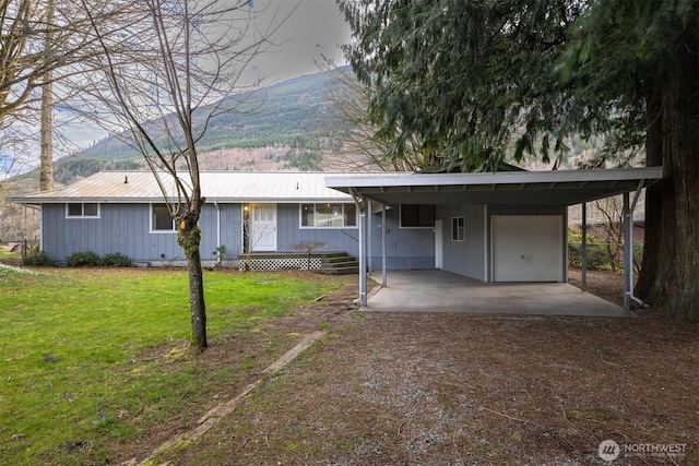 ranch-style home featuring a front lawn, dirt driveway, metal roof, a carport, and a mountain view