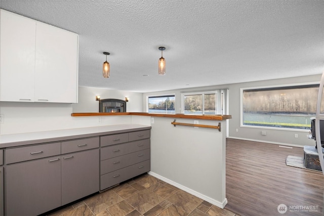 kitchen with baseboards, light countertops, gray cabinets, a peninsula, and white cabinetry