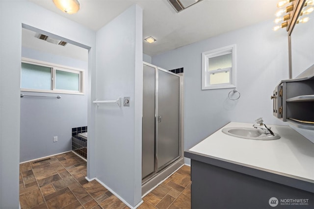 bathroom featuring vanity, stone finish floor, a healthy amount of sunlight, and a stall shower