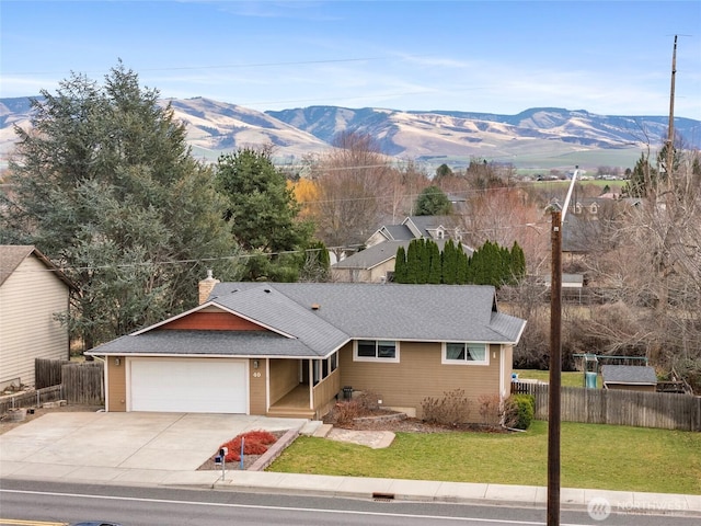 single story home featuring concrete driveway, fence, a front lawn, and a mountain view