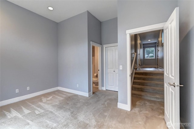 unfurnished bedroom with recessed lighting, baseboards, carpet, and ensuite bath