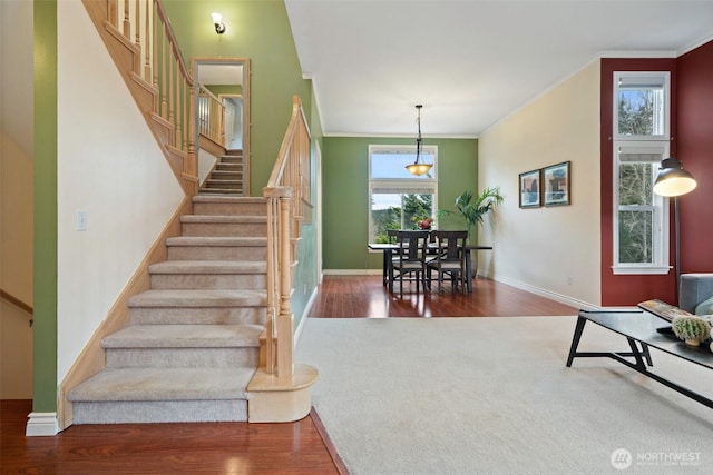 stairway featuring baseboards, ornamental molding, and wood finished floors