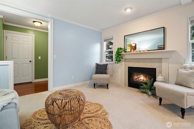 living area featuring ornamental molding, baseboards, carpet floors, and a tiled fireplace