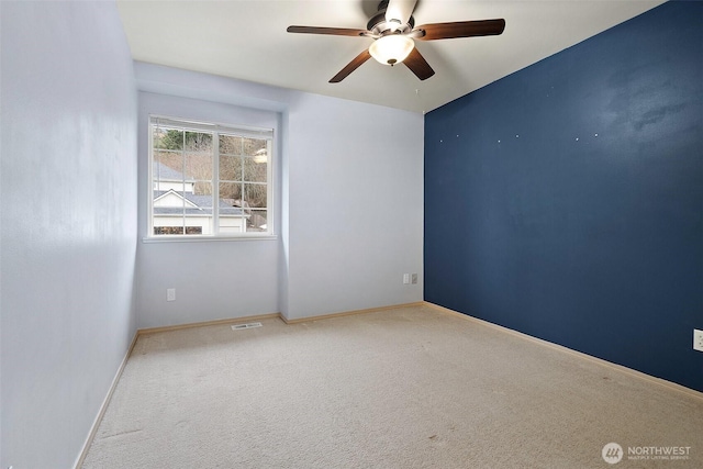 carpeted empty room featuring baseboards, visible vents, and a ceiling fan