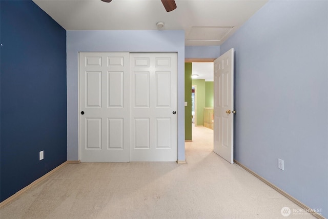 unfurnished bedroom featuring attic access, a closet, carpet flooring, and a ceiling fan