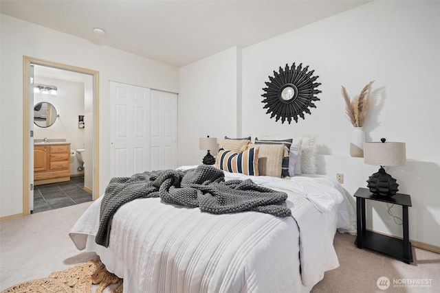 bedroom with ensuite bath, a closet, baseboards, and carpet flooring