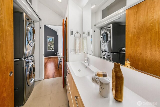 bathroom with tile patterned floors, stacked washer and clothes dryer, vanity, and lofted ceiling