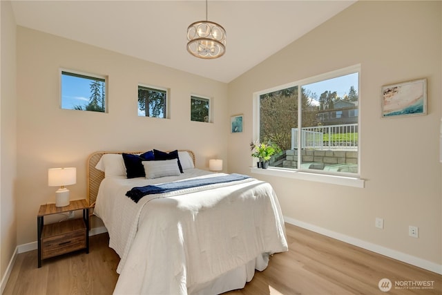 bedroom with lofted ceiling, a chandelier, wood finished floors, and baseboards