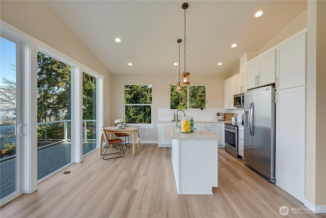 kitchen with light countertops, appliances with stainless steel finishes, light wood-style floors, white cabinetry, and vaulted ceiling