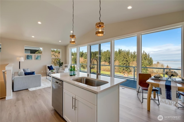 kitchen featuring light countertops, hanging light fixtures, open floor plan, a sink, and dishwasher