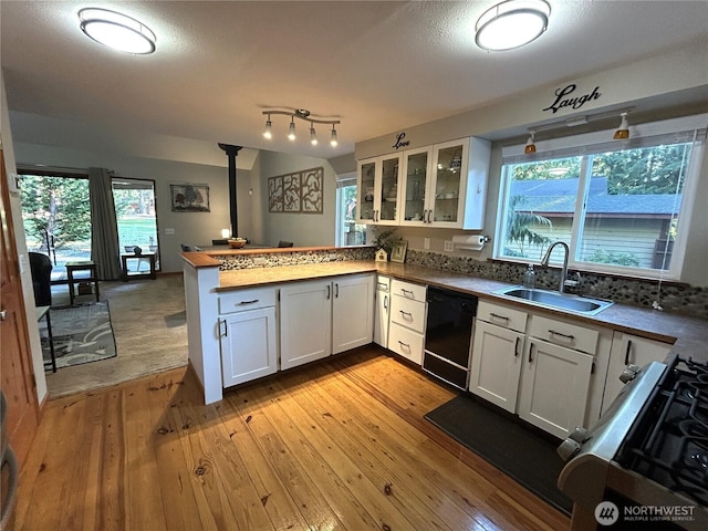 kitchen featuring black dishwasher, glass insert cabinets, a peninsula, white cabinetry, and a sink