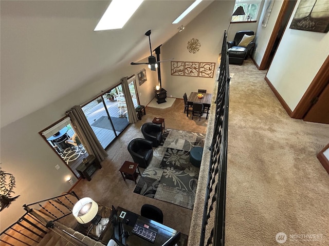 carpeted living room featuring a skylight, baseboards, high vaulted ceiling, and ceiling fan