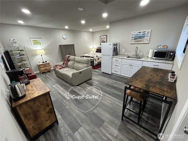 living area with dark wood-style flooring and recessed lighting