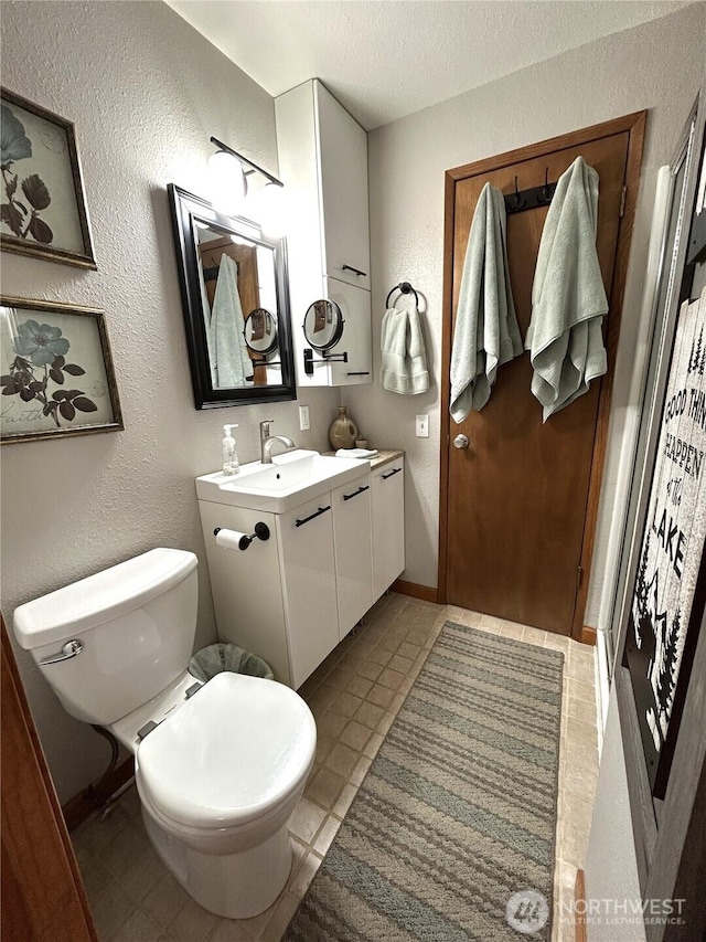 full bath with baseboards, a textured wall, a textured ceiling, and toilet