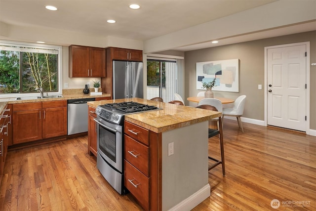 kitchen featuring appliances with stainless steel finishes, light countertops, a kitchen bar, and a sink